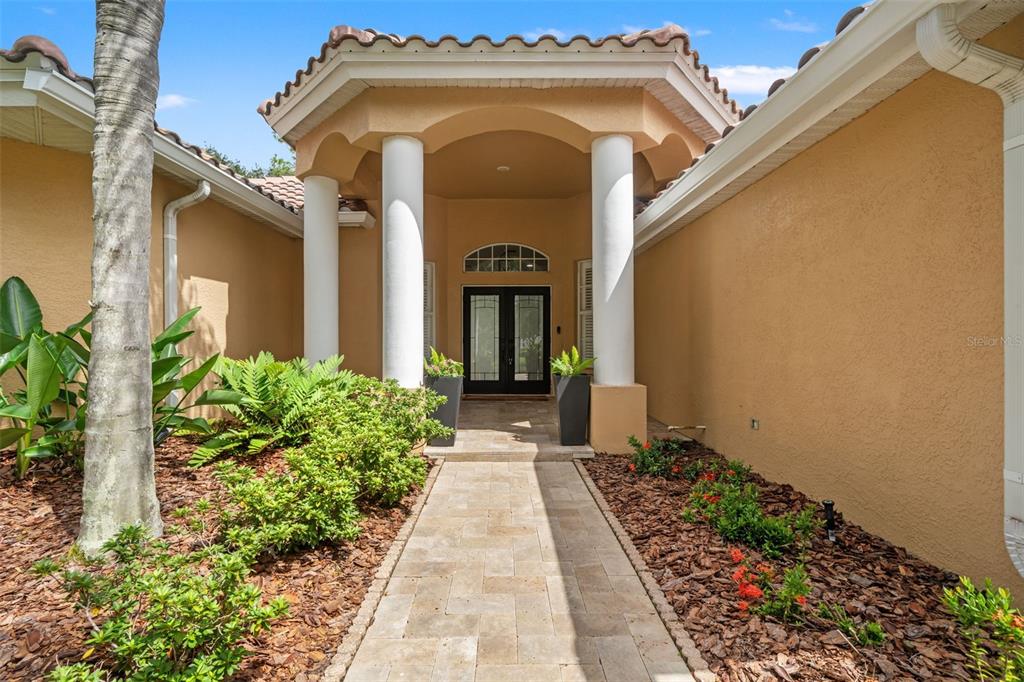 A paved walkway leads to a covered front entryway with two white columns and double doors — 18115 REGENTS SQUARE DRIVE, TAMPA, FL