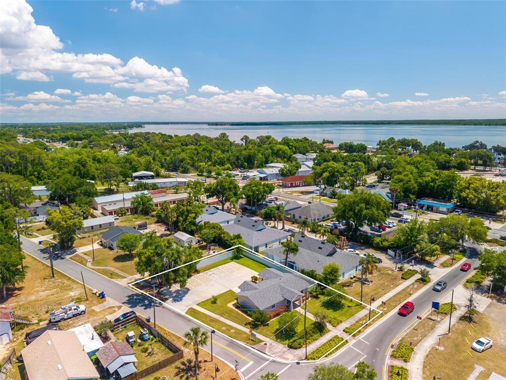 An aerial view shows a single-story house with a parking lot near a large lake — 322 N DISSTON AVENUE, TAVARES, FL