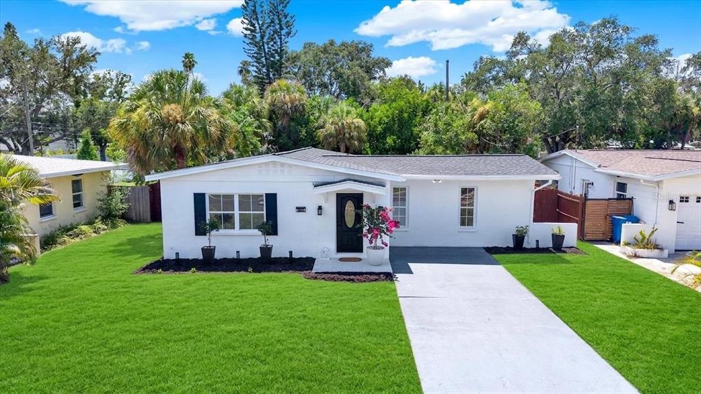 A white single-story house with a black front door, dark shutters, and a concrete driveway — 4200 HUNTINGTON STREET NE, ST PETERSBURG, FL