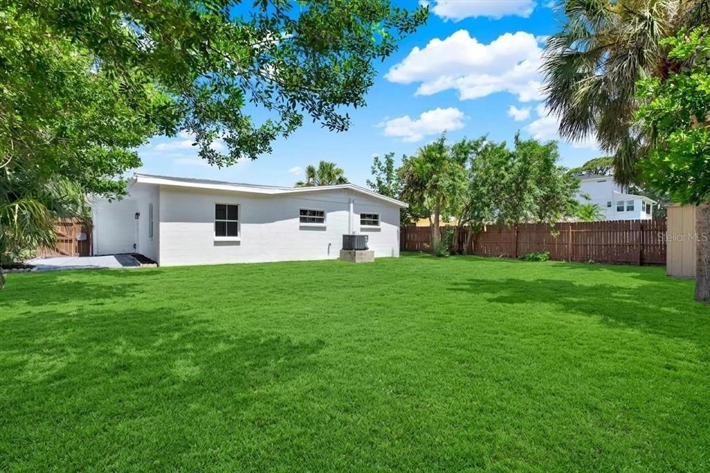 A white house with a large green lawn and a wooden fence in the backyard — 4200 HUNTINGTON STREET NE, ST PETERSBURG, FL