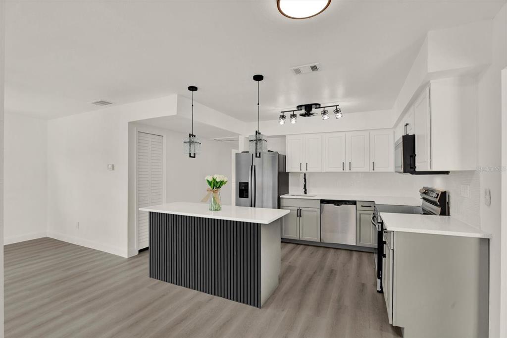 A modern kitchen features a dark slatted island, white cabinetry, and light wood-look flooring — 4200 HUNTINGTON STREET NE, ST PETERSBURG, FL