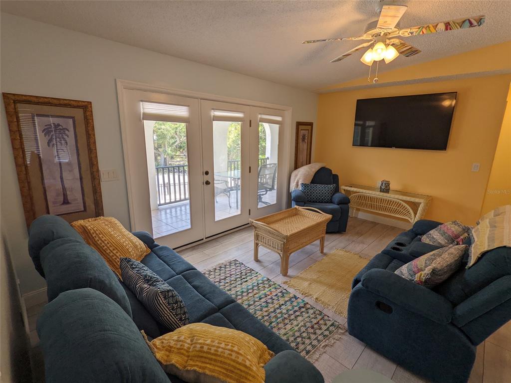 A living room features blue sofas, a wicker coffee table, and French doors leading outside — 203 CANOVA DRIVE, NEW SMYRNA BEACH, FL