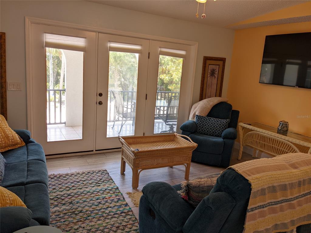 A living room features blue furniture, a wicker coffee table, and glass doors to a balcony — 203 CANOVA DRIVE, NEW SMYRNA BEACH, FL
