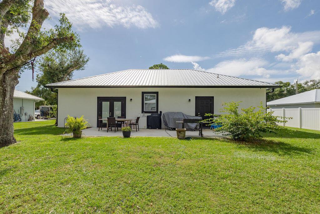 The exterior of a white house with a metal roof features a concrete patio — 1014 SW 11th Street, Okeechobee FL 34974, OKEECHOBEE, FL