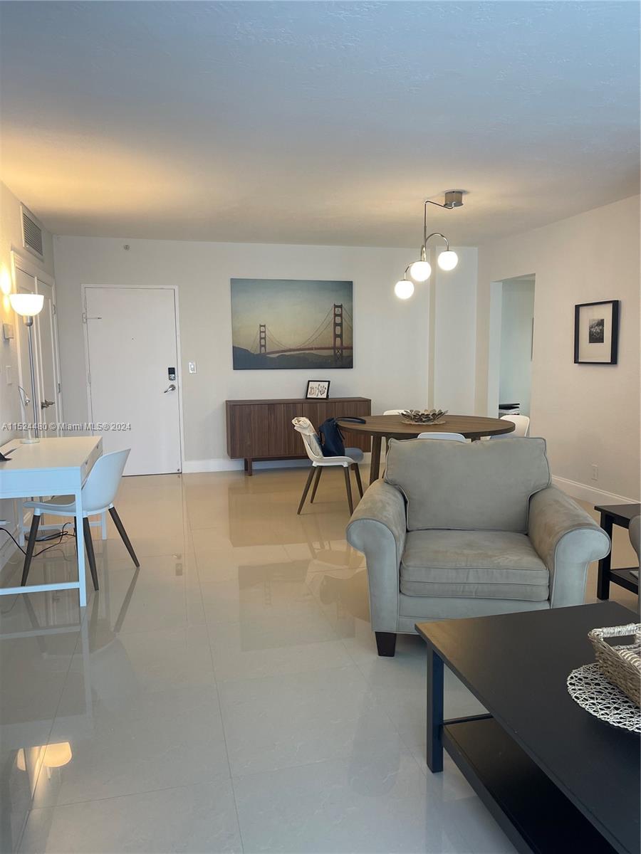 A living and dining area features white tile floors, a round table, and a beige armchair — 3801 S OCEAN DR # 15V, Hollywood FL 33019, HOLLYWOOD, FL