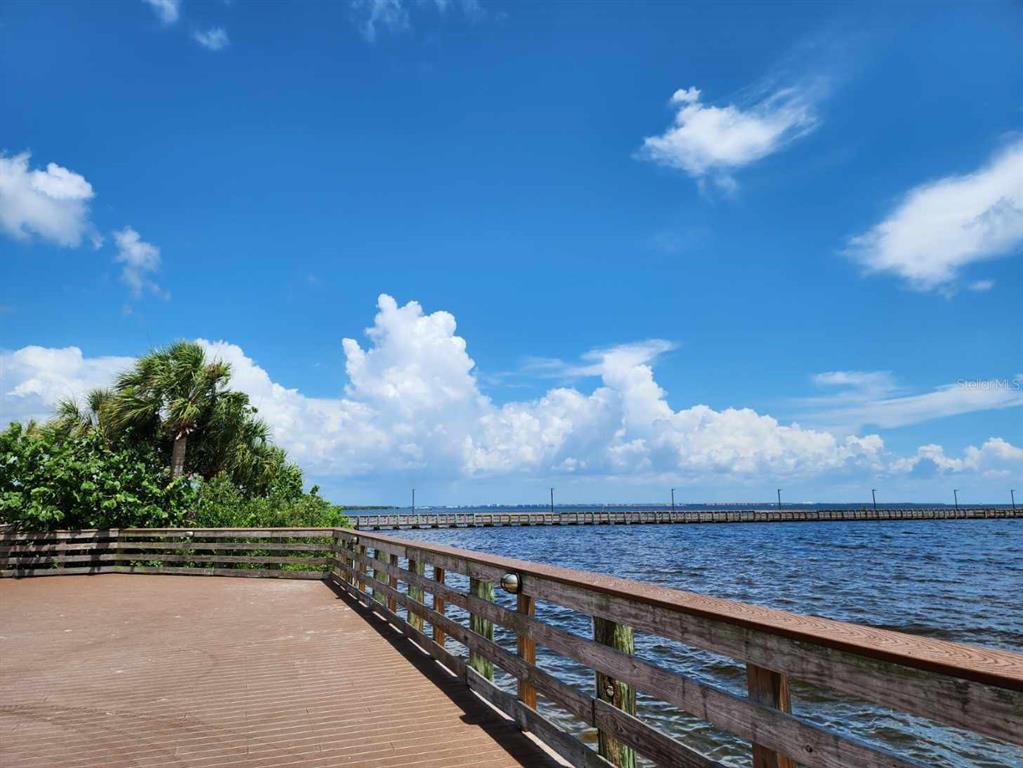A wooden deck with a railing overlooks a large body of water and a pier — 3135 CABARET STREET, PORT CHARLOTTE, FL