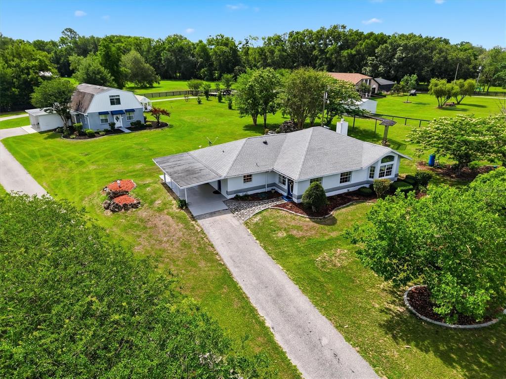 An aerial view shows a single-story house with a carport and a detached barn-style building — 6935 NW HIGHWAY 225A, OCALA, FL