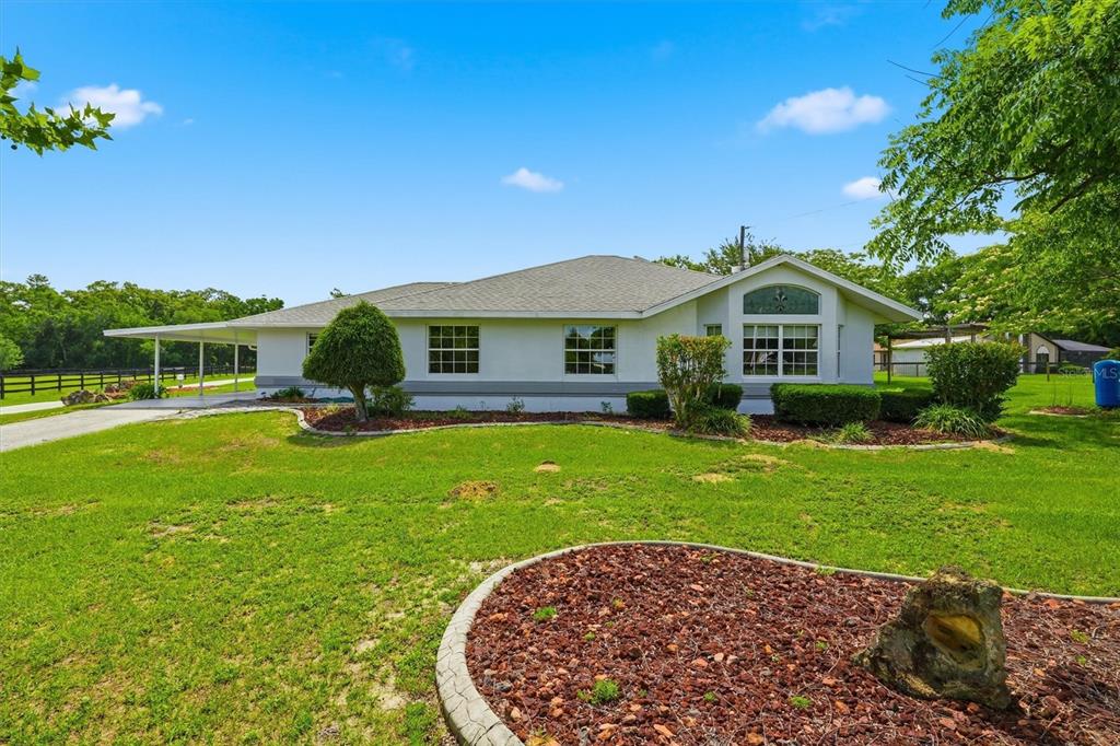 A white single-story house with a gray shingled roof and a side carport — 6935 NW HIGHWAY 225A, OCALA, FL