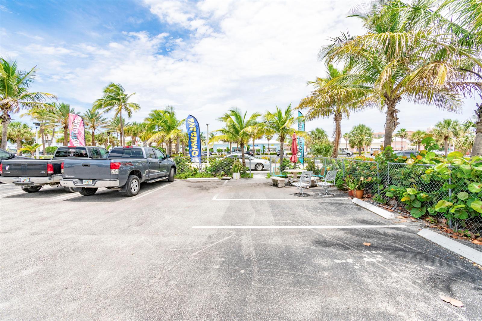 A parking lot with two pickup trucks, palm trees, and a small outdoor seating area — 1281 Plaza Circle, FL, FL