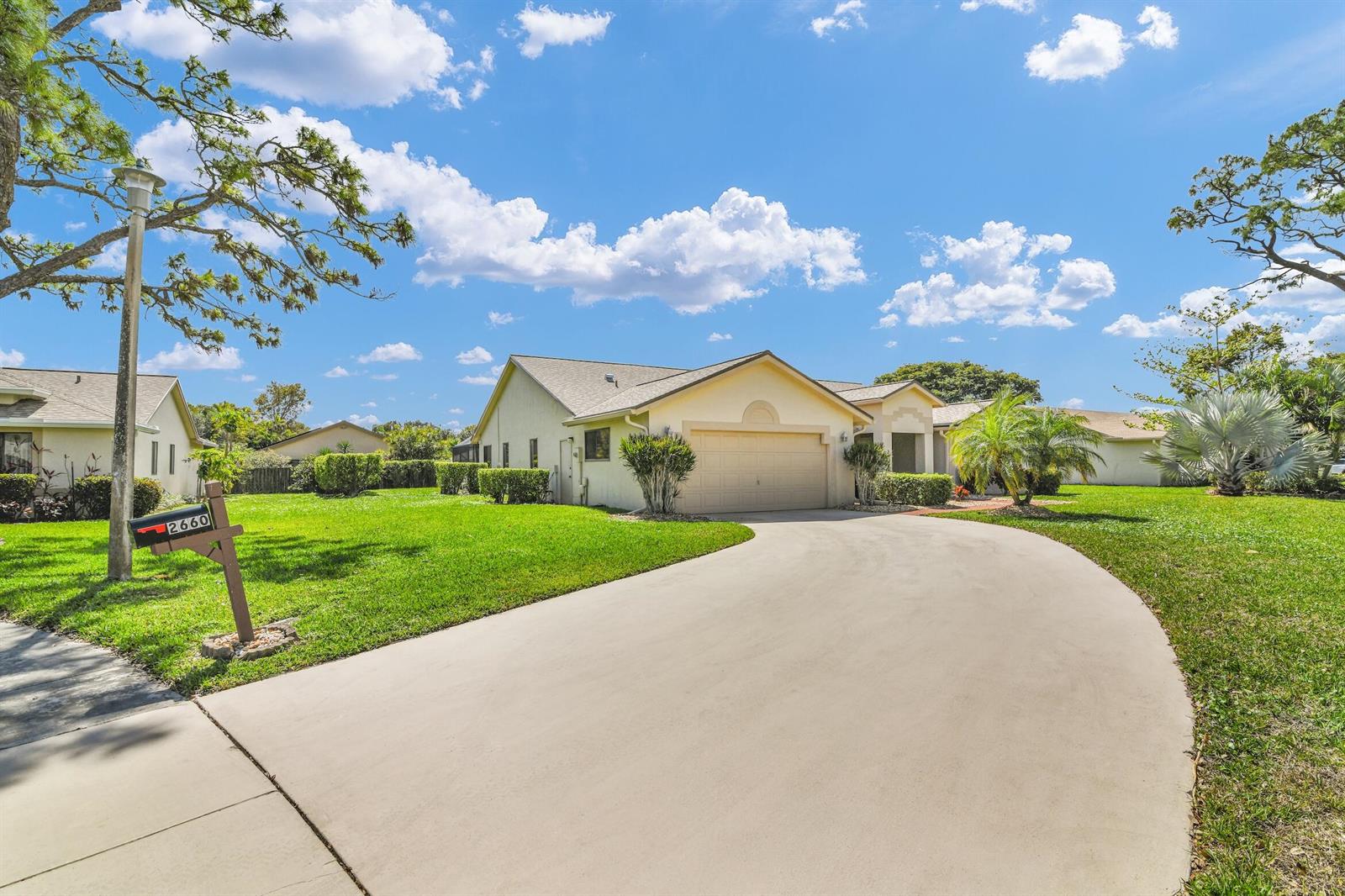 A single-story house with a beige exterior, a two-car garage, and a curved concrete driveway — 2660 Riviera Drive, Delray Beach FL 33445, DELRAY BEACH, FL