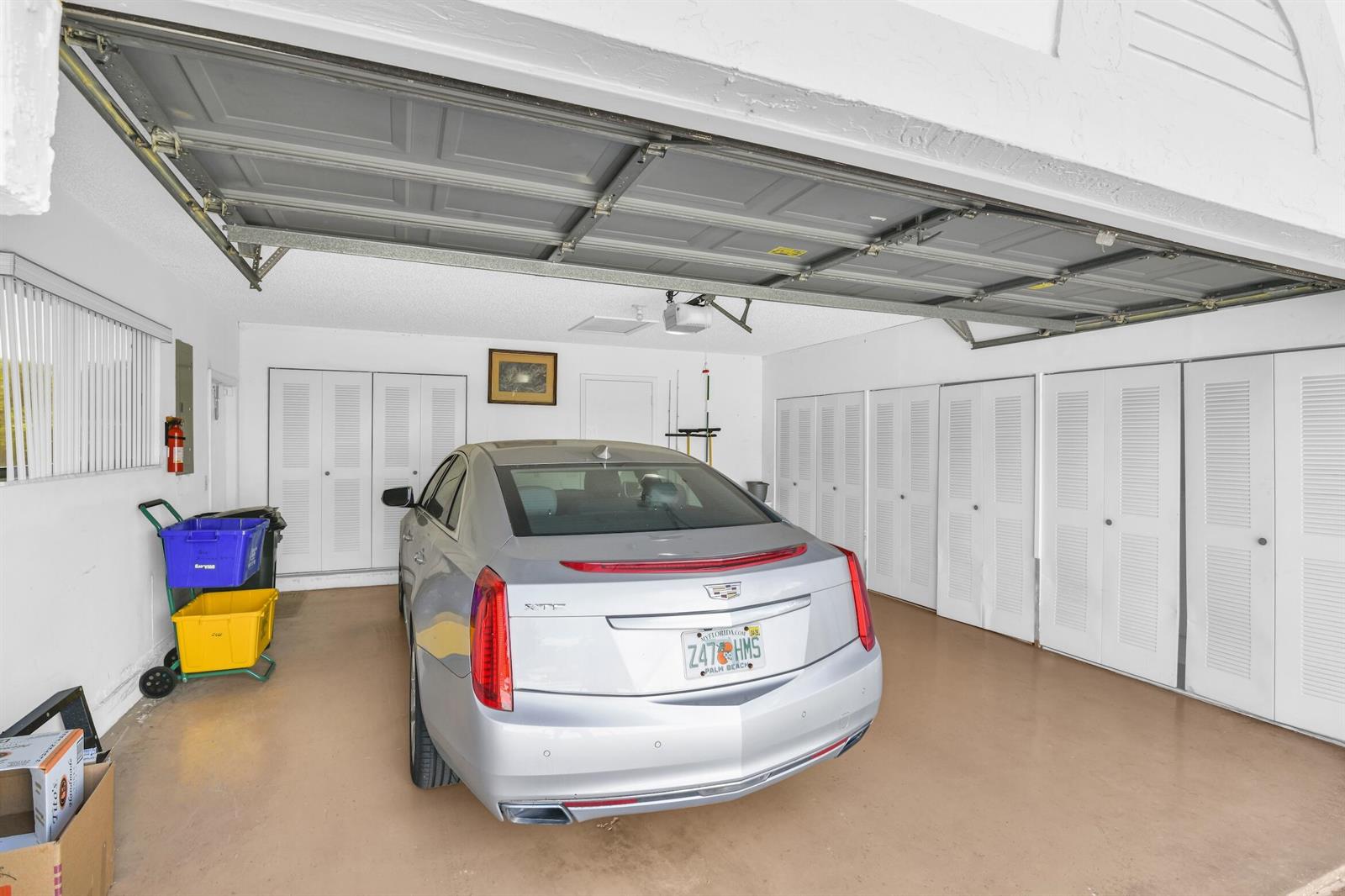 A silver sedan is parked inside a garage with white walls and multiple storage closets — 2660 Riviera Drive, Delray Beach FL 33445, DELRAY BEACH, FL