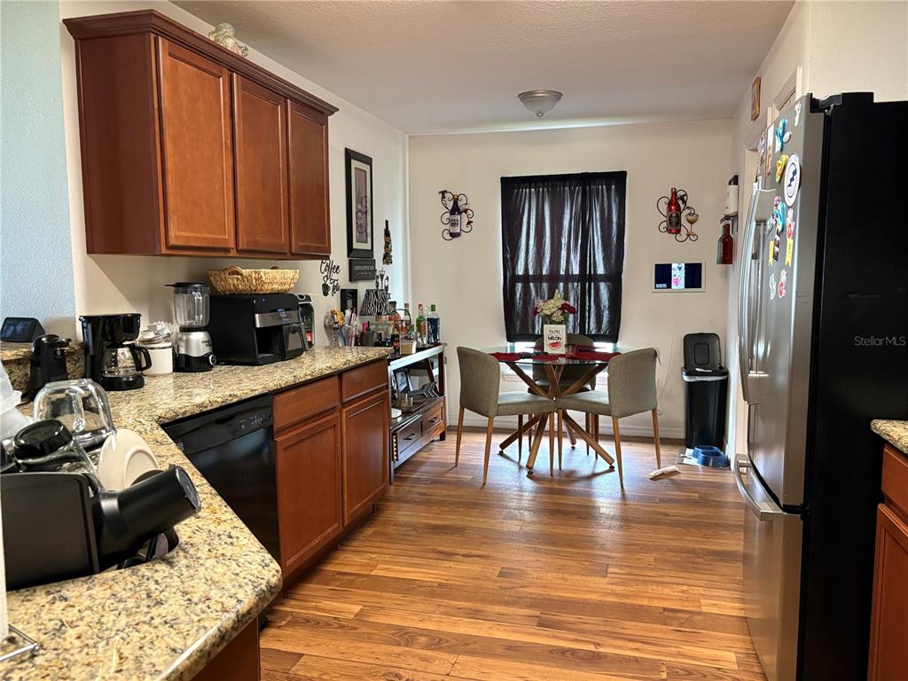 A kitchen with wood cabinets, granite countertops, and a small dining area with a table — 14217 ALISTAR MANOR DRIVE, WIMAUMA, FL