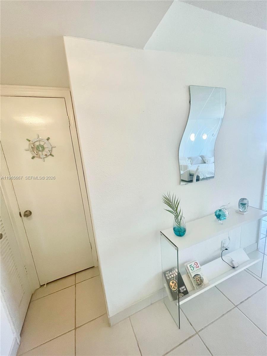 A white door with a nautical decoration sits beside a glass console table and mirror — 1817 S Ocean Dr # 219, Hallandale Beach FL 33009, HALLANDALE BEACH, FL