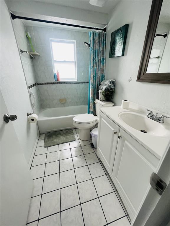 A bathroom features a white vanity, a toilet, and a bathtub with a shower curtain — 7705 ILEX DRIVE, PORT RICHEY, FL