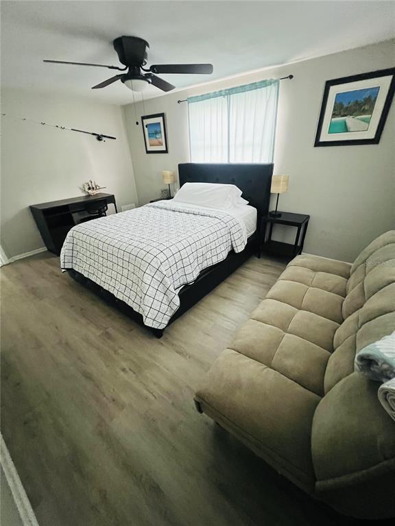 A bedroom features a bed, a sofa, a desk, and wood-look flooring — 7705 ILEX DRIVE, PORT RICHEY, FL