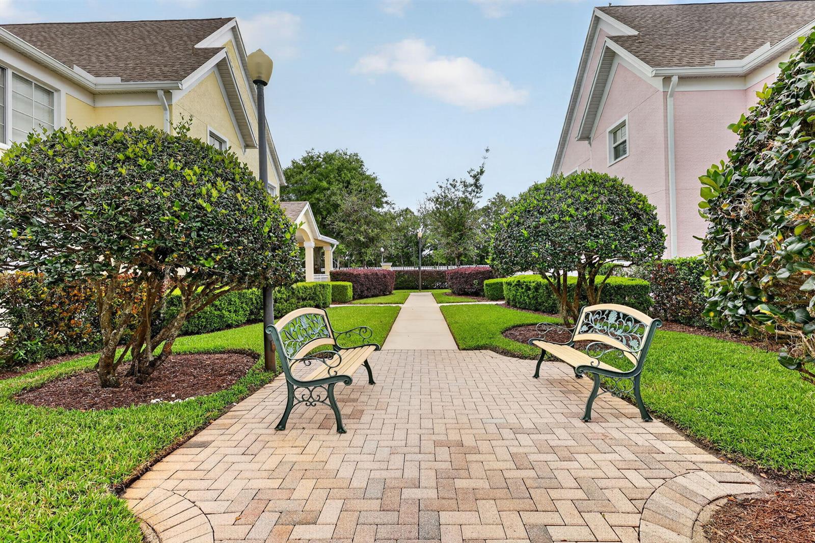 A paved walkway with two benches sits between two residential buildings and manicured landscaping — 1679 SE Pomeroy Street # 1, Stuart FL 34997, STUART, FL