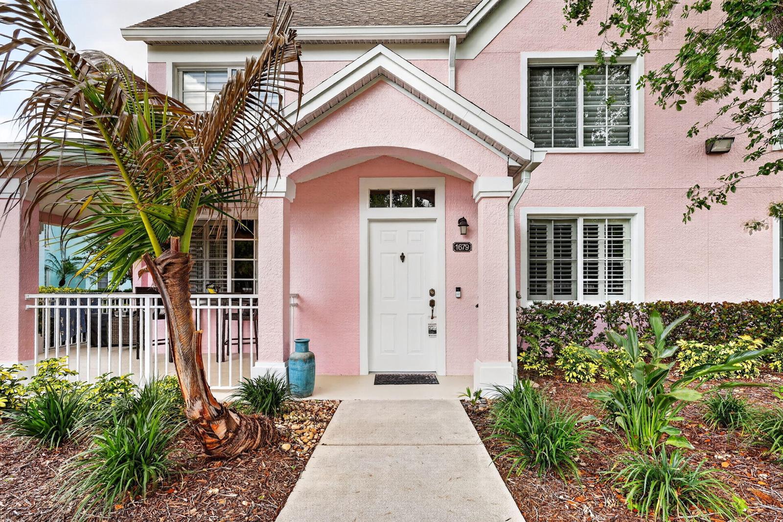 A pink two-story house features a white front door, a covered porch, and a palm tree — 1679 SE Pomeroy Street # 1, Stuart FL 34997, STUART, FL