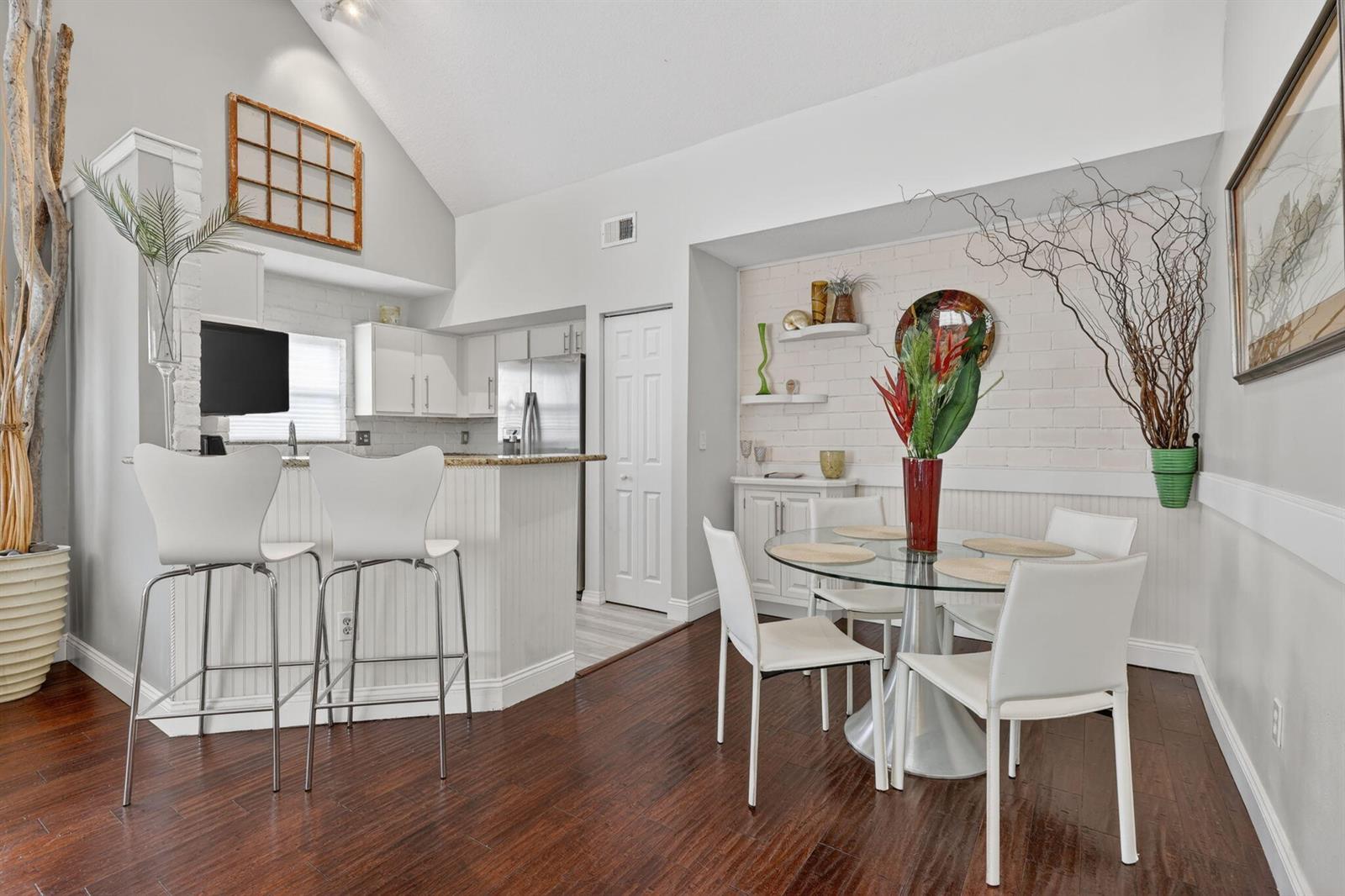 A dining area and kitchen feature white cabinetry, a breakfast bar, and dark wood flooring — 1679 SE Pomeroy Street # 1, Stuart FL 34997, STUART, FL