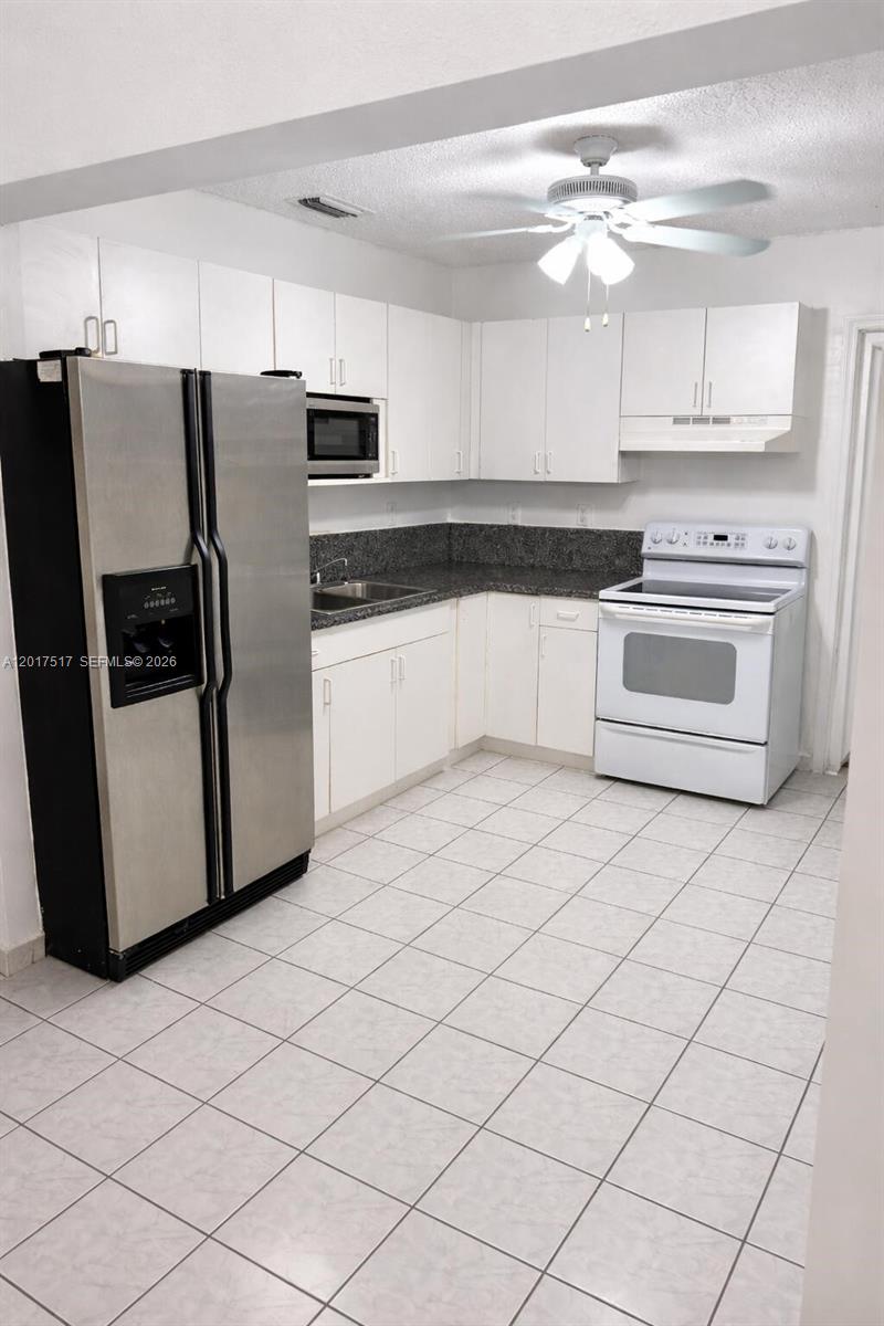 A kitchen features white cabinets, stainless steel appliances, dark countertops, and light-colored floor tiles — 538 E 13th St, Hialeah FL 33010, HIALEAH, FL