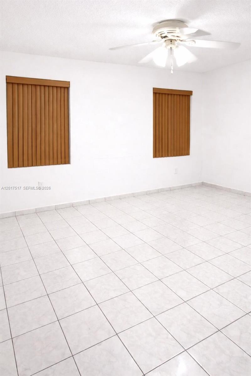 An empty room features white walls, light-colored tile flooring, and two windows with vertical blinds — 538 E 13th St, Hialeah FL 33010, HIALEAH, FL