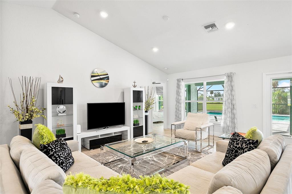 A living room features a white sectional sofa, a glass coffee table, and a pool view — 240 CADDY ROAD, ROTONDA WEST, FL