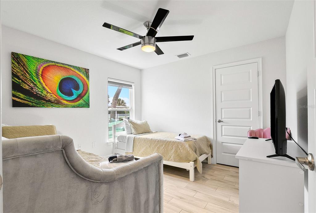 A bedroom features two beds, a ceiling fan, a peacock feather print, and light flooring — 240 CADDY ROAD, ROTONDA WEST, FL