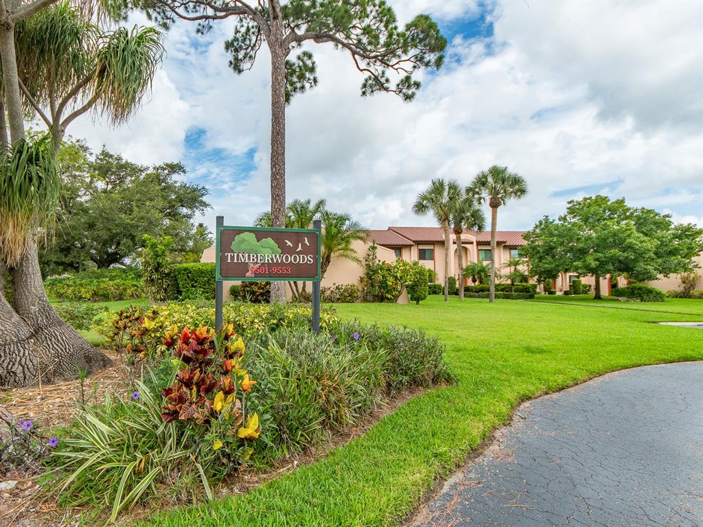 A sign for Timberwoods stands in a grassy yard in front of a multi-story building — 9543 86TH AVENUE UNIT 9543, SEMINOLE, FL