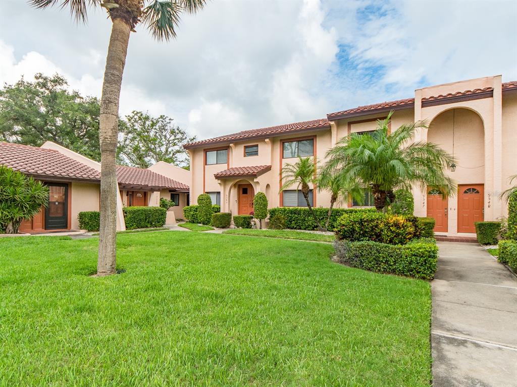 A two-story apartment building with a lawn, palm trees, and orange doors — 9543 86TH AVENUE UNIT 9543, SEMINOLE, FL