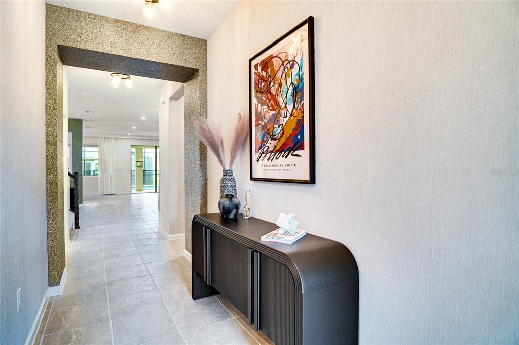 A hallway features a dark console table, abstract wall art, and a textured arched entryway — 2341 SALTY WINDS WAY, KISSIMMEE, FL