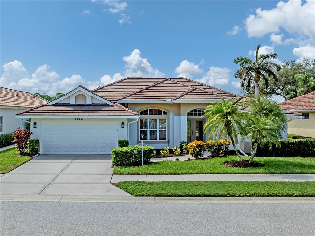 A single-story house with a tiled roof, a two-car garage, and a landscaped front yard — 5078 WINTER ROSE WAY, VENICE, FL