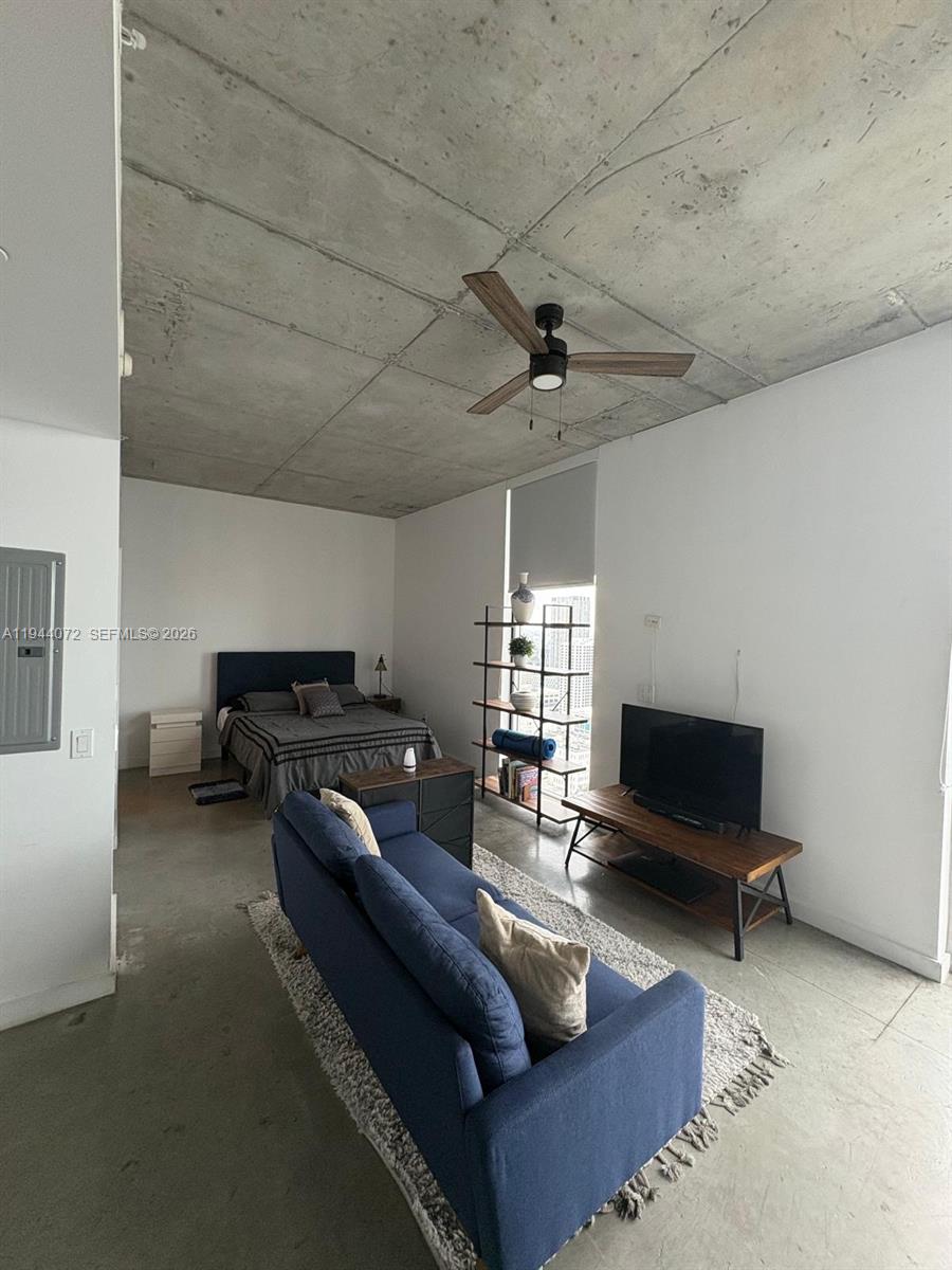 A studio apartment features a concrete ceiling, polished concrete floors, and a blue sofa — 151 SE 1st St # 3404, Miami FL 33131, MIAMI, FL