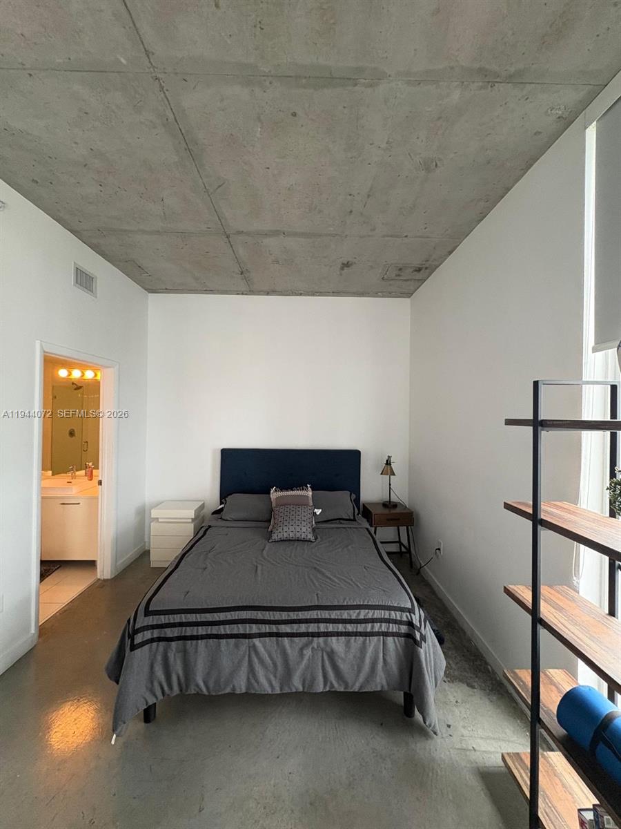 A bedroom features a bed, concrete ceiling, and an attached bathroom with white cabinetry — 151 SE 1st St # 3404, Miami FL 33131, MIAMI, FL