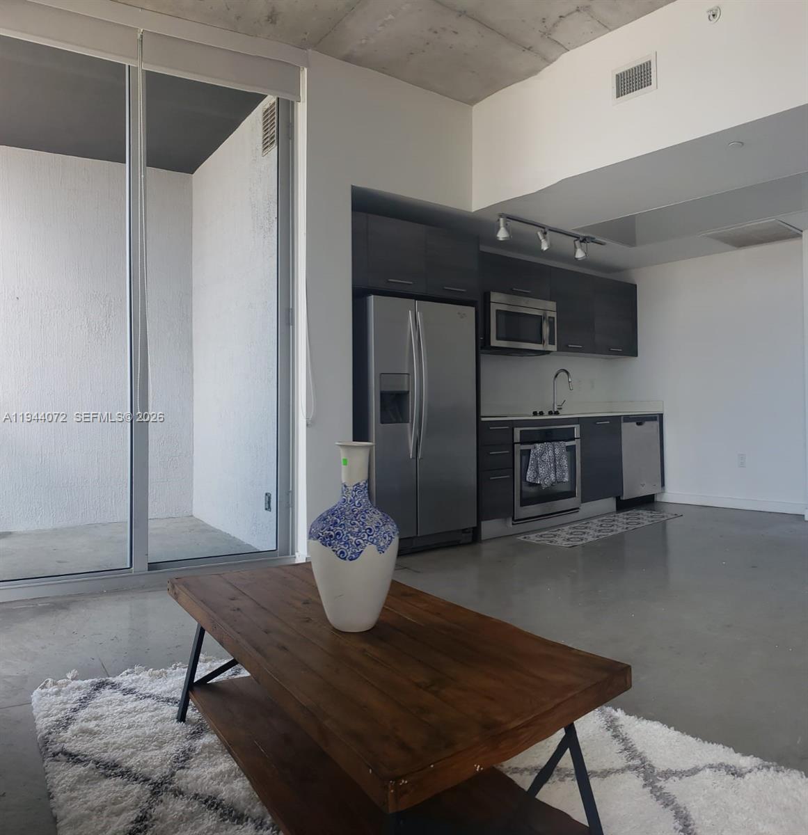 A modern kitchen with dark cabinets and stainless steel appliances overlooks a living area — 151 SE 1st St # 3404, Miami FL 33131, MIAMI, FL