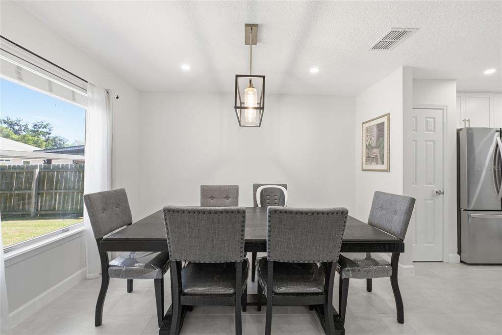 A dining room features a dark wood table, gray upholstered chairs, and a pendant light — 10251 TREVOR CREEK DRIVE W, JACKSONVILLE, FL