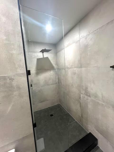 A walk-in shower features large gray tiles, a glass panel, and a black shower head — 739 SE 12th Avenue, Deerfield Beach FL 33441, DEERFIELD BEACH, FL