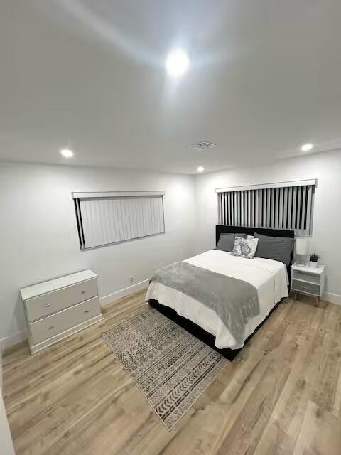 A bedroom features light wood flooring, a bed with gray bedding, and a white dresser — 739 SE 12th Avenue, Deerfield Beach FL 33441, DEERFIELD BEACH, FL