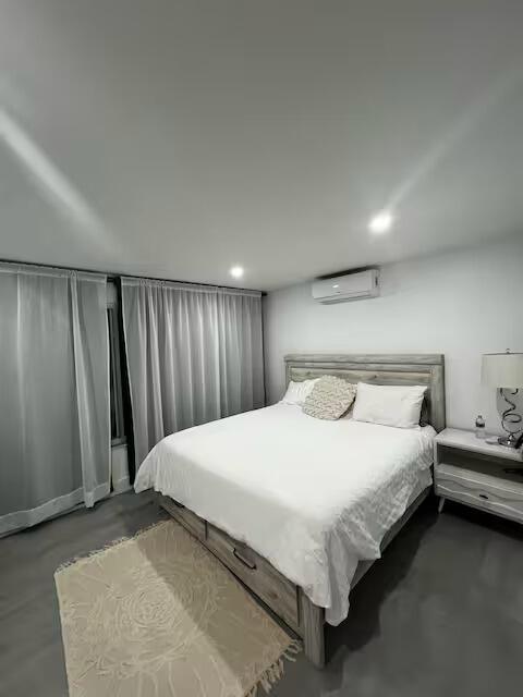 A bedroom features a wooden bed frame, sheer curtains, and a nightstand with a lamp — 739 SE 12th Avenue, Deerfield Beach FL 33441, DEERFIELD BEACH, FL