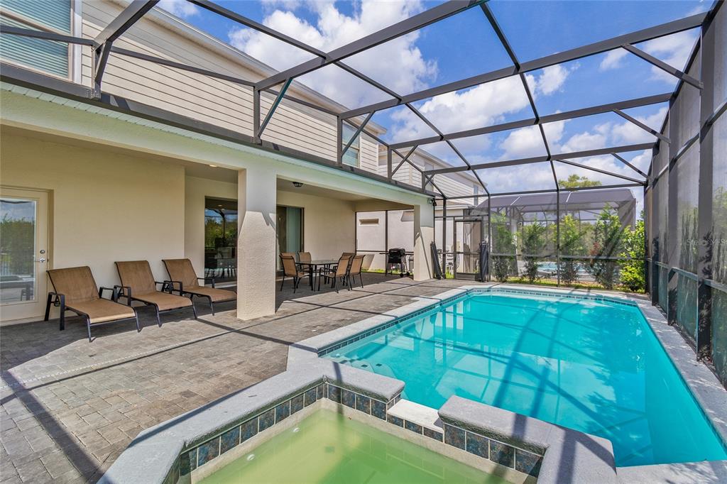 A screened-in patio features a swimming pool, a hot tub, and outdoor seating — 2451 LUXOR DRIVE, KISSIMMEE, FL