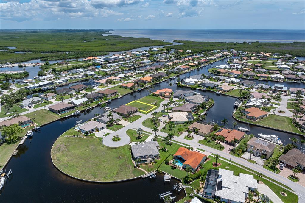 An aerial view shows a vacant residential lot highlighted in yellow within a canal community — 1237 WHIPPOORWILL COURT, PUNTA GORDA, FL