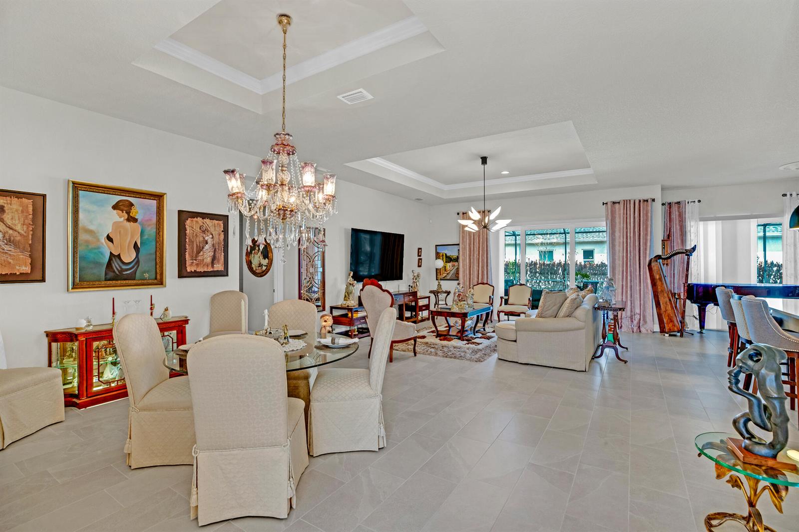 An open-concept living and dining area features a crystal chandelier, tile floors, and a harp — 4160 Negal Circle, Melbourne FL 32901, MELBOURNE, FL