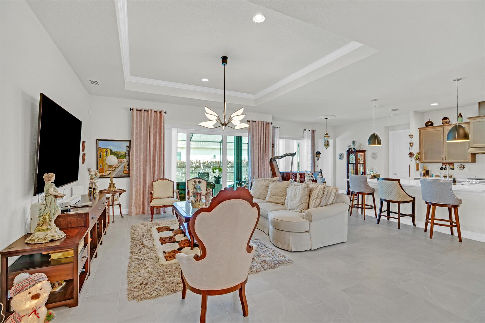 A living room with a tray ceiling, beige sofa, and an open kitchen with bar stools — 4160 Negal Circle, Melbourne FL 32901, MELBOURNE, FL