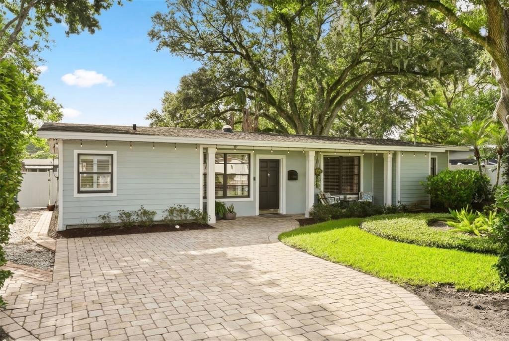 A light blue, single-story house features a paved driveway and a front lawn with trees — 1562 ARBOR PARK DRIVE, WINTER PARK, FL