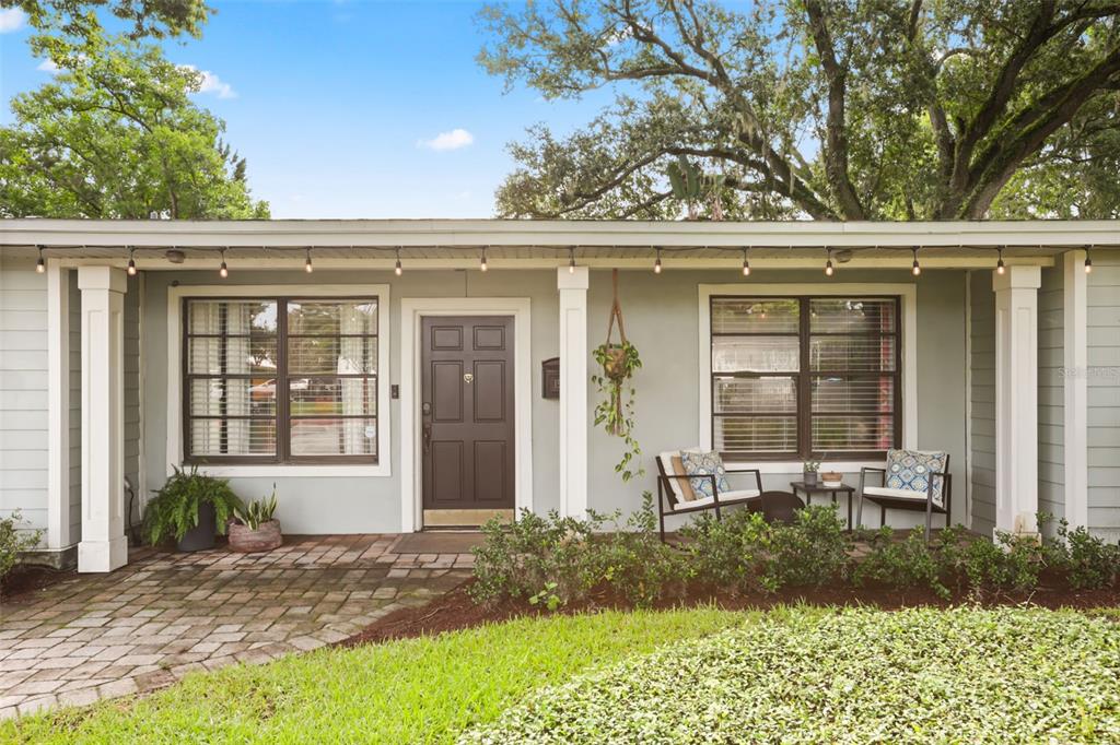 The exterior of a single-story house features a brick patio, a dark door, and columns — 1562 ARBOR PARK DRIVE, WINTER PARK, FL