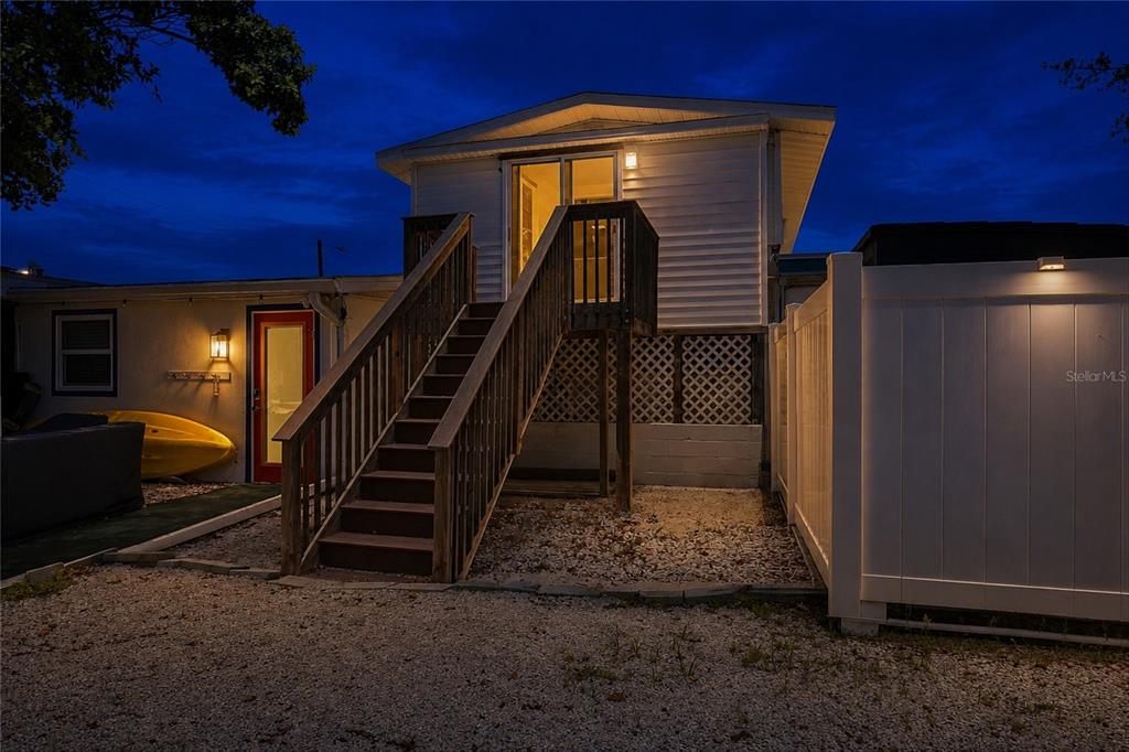 An exterior view of a raised house with wooden stairs leading to a sliding glass door — 455 62ND STREET, HOLMES BEACH, FL