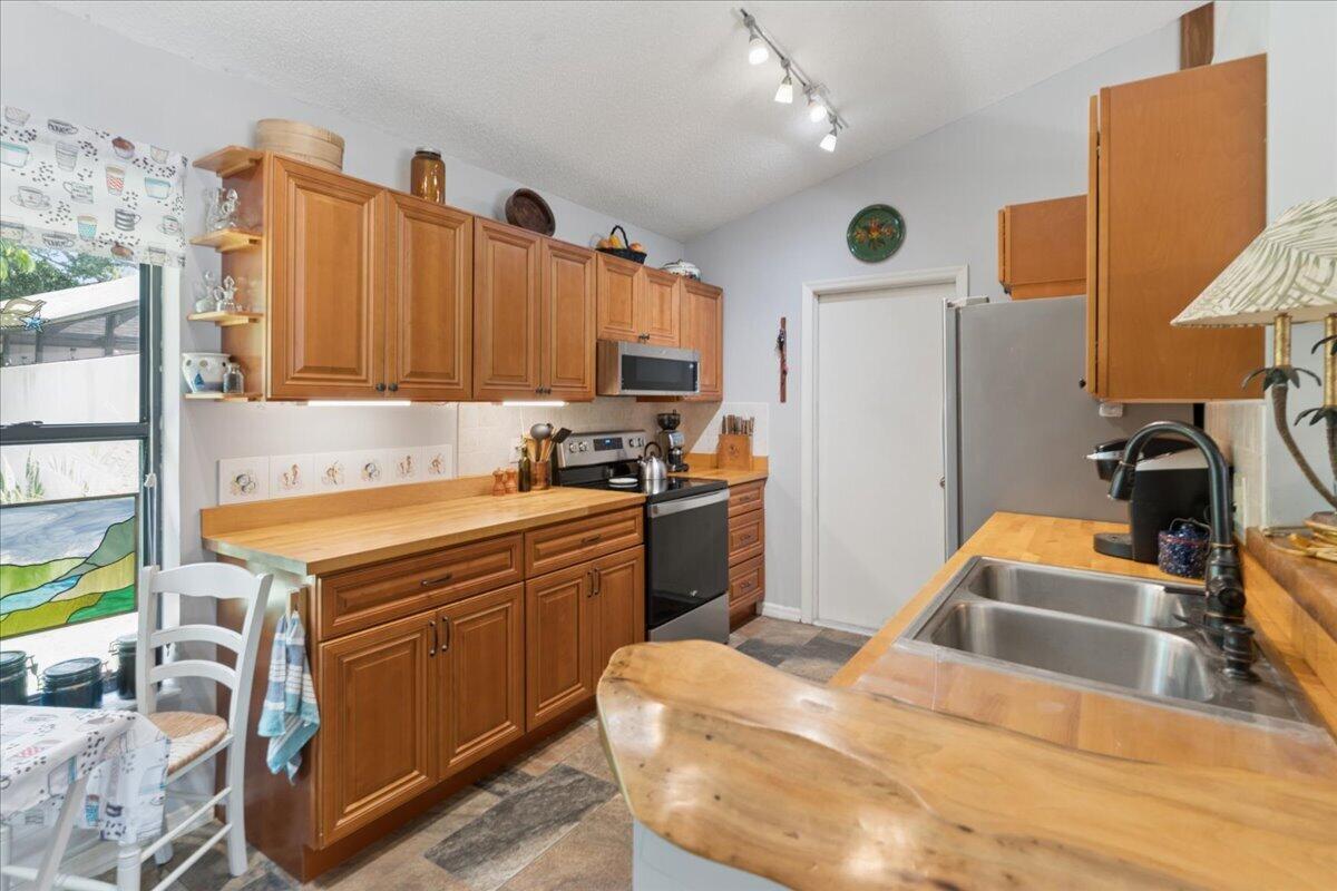 A kitchen with wood cabinets, butcher block countertops, stainless steel appliances, and a double sink — 6287 N Mirror Lake Drive, Sebastian FL 32958, SEBASTIAN, FL