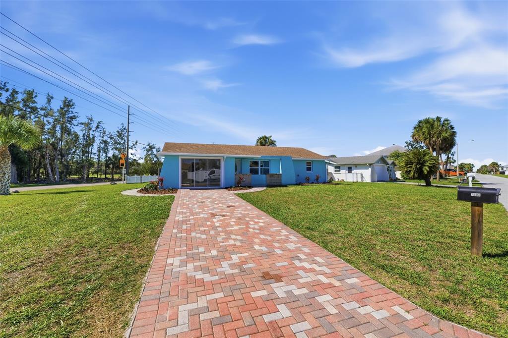 A light blue single-story house features a brick paver walkway leading to the front entrance — 7608 YACHTSMAN DRIVE, HUDSON, FL