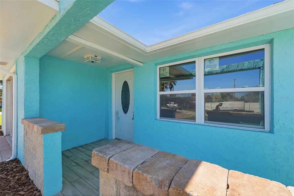 A bright blue exterior wall features a white front door and a double-hung window — 7608 YACHTSMAN DRIVE, HUDSON, FL