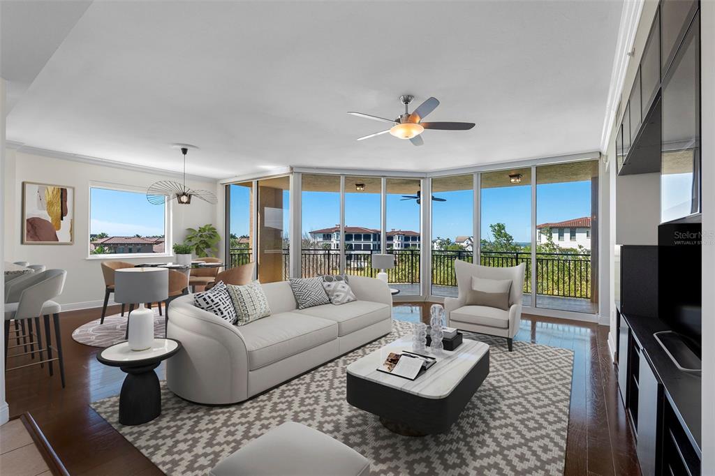 A living room features a white sofa, a patterned rug, and floor-to-ceiling windows overlooking balconies — 5823 BOWEN DANIEL DRIVE UNIT 401, TAMPA, FL
