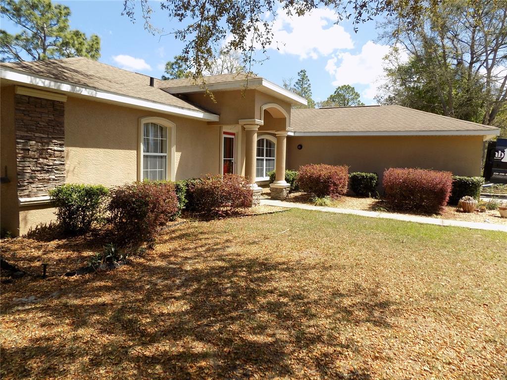 A single-story house with a tan stucco exterior, stone accents, and a covered front entrance — 2047 W PARAGON LANE, CITRUS SPRINGS, FL