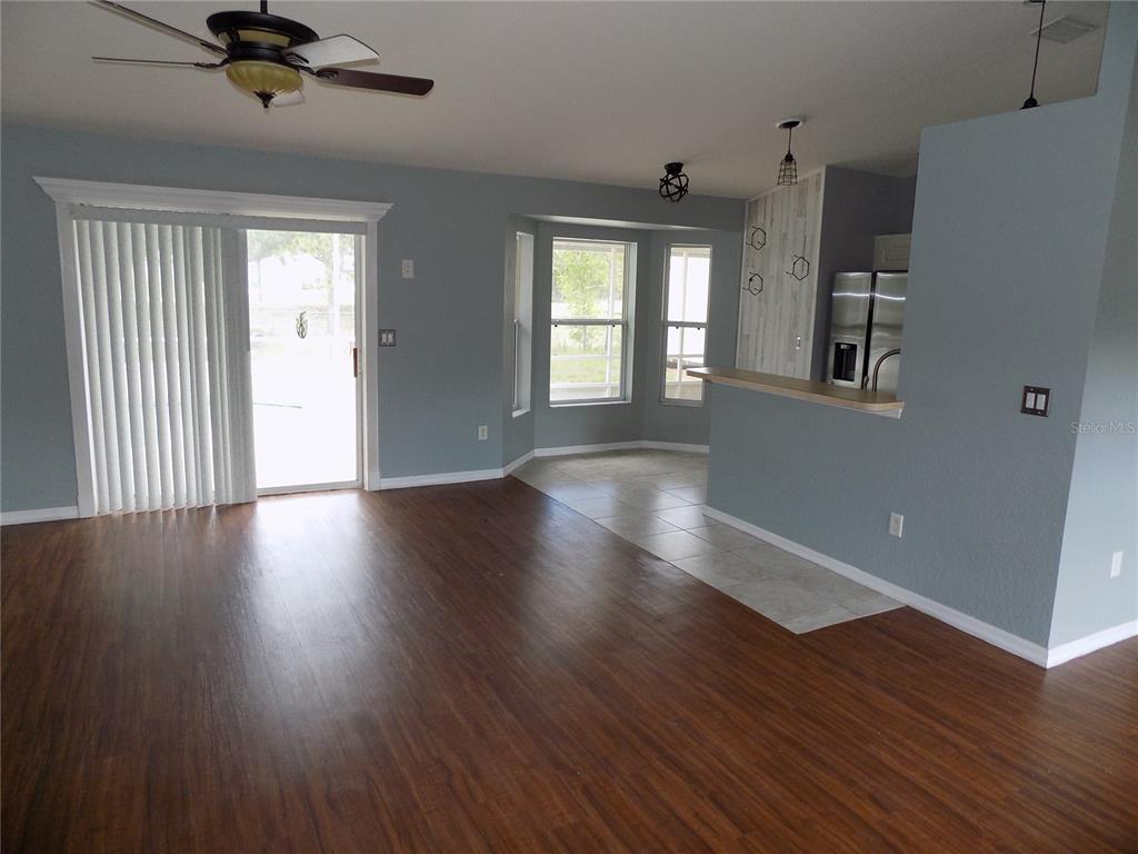 A living room with wood-look flooring, a ceiling fan, and a kitchen with a breakfast bar — 2047 W PARAGON LANE, CITRUS SPRINGS, FL
